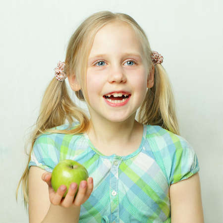 Laughing little girl with green appleの写真素材