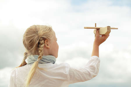 Girl and airplane toy on the cloudy sky backgroundの写真素材