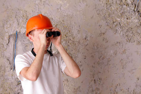 builder with binoculars at the background of the gray plastered wallsの写真素材