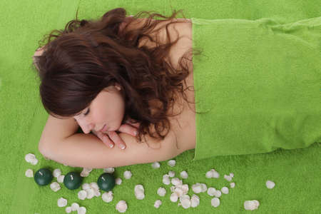 young beautiful woman relaxing on green background in spa centerの写真素材
