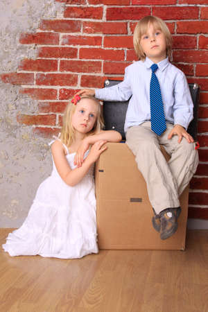 Beautiful tired children sitting on suitcasesの写真素材