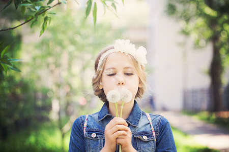 Beautiful Young Girl with Blonde Hair. Prom Hairstyle and Dandelion Flowersの写真素材