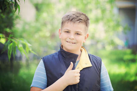 Young Boy Showing Thumbs Up Gesture Outdoorsの写真素材