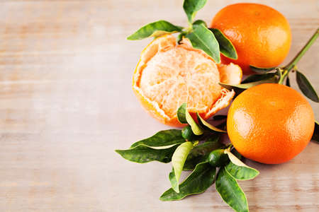 Ripe Mandarin Fruit  and Green Leaves on Old Rustic Wooden Board Backgroundの写真素材