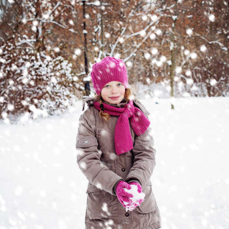 Smiling Child Girl Playing with Snow in Winter Park Outdoorsの写真素材