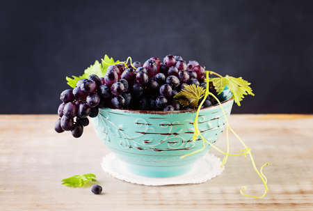 Grape and Grapevine with Green Leaves on Rustic Wooden Board Backgroundの写真素材