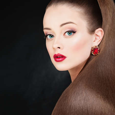 Pretty Model Woman with Long Healthy Smooth Brown Hair and Makeup. Perfect Ponytail Hairstyle. Beautiful Girl on Dark Backgroundの写真素材