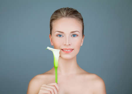 Natural Beauty. Healthy Woman with Lily Flower Smiling on Blue Backgroundの写真素材