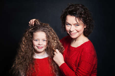 Smiling Mother and Daughter with Long Curly Hair. Happy Woman and Childの写真素材