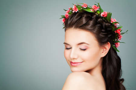 Healthy Spa Model Woman Relaxing on Blue Background. Spa Girl with Natural Nude Make up, Wavy Hair and Summer Flowers Wreathの写真素材