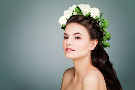 Cute Brunette Model Woman with Prom Hairstyle, Makeup and White Flowers on Blue Backgroundの写真素材