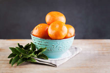 Dessert. Mandarin Fruit and Green Leaves on Wooden Board Backgroundの写真素材