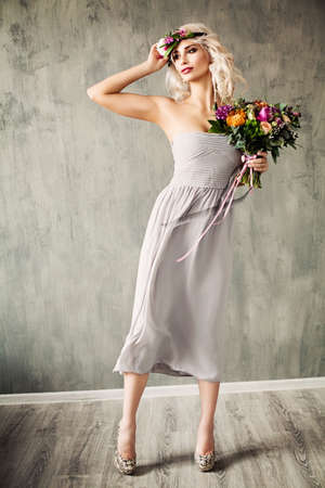 Summer Beauty Portrait of Beautiful Blonde Model Woman with Blonde Hair, Blowing Dress and Flowersの写真素材