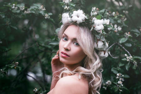 Spring Model Girl with Long Bob Hairstyle. Glamour Woman with Blonde Wavy Hair on Flowers Backgroundの写真素材