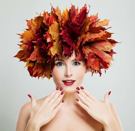 Autumn Concept. Beautiful Woman with Wreath of Red Maple Leaves, Autumn Fashion Makeup and Manicureの写真素材