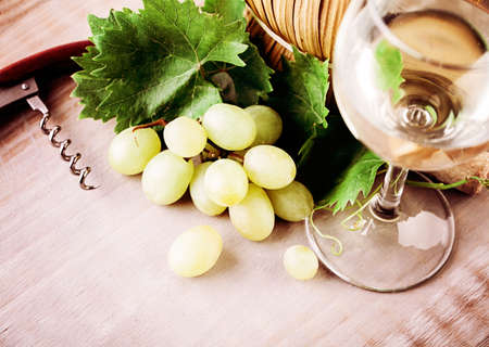 Wine, Glass, Grape and Grapevine with Green Leaves on Rustic Wooden Board Backgroundの写真素材