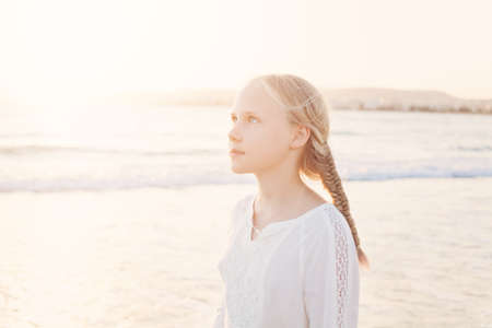 Happy Young Girl Walking at the Beach under the Morning Sunの写真素材