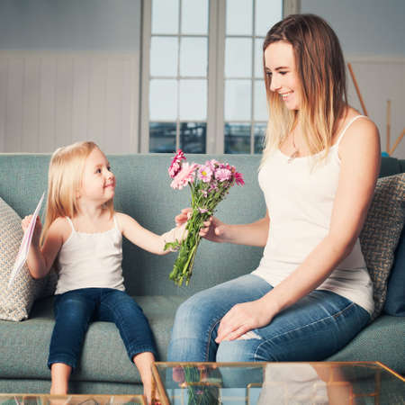 Happy Woman and Child Girl with Flowers at Home. Loving Daughter and Motherの写真素材