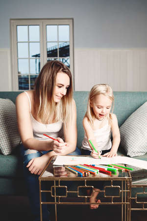 Loving Family. Woman and Child Drawing at Home. Smiling Daughter and Mom Paintingの写真素材