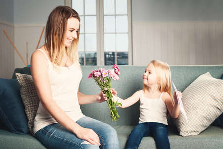 Mother's Day. Woman and Child with Flowers and Gift Card. Smiling Daughter and Motherの写真素材