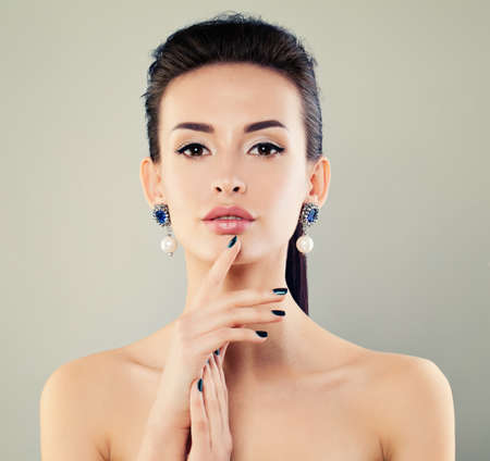 Perfect Female Face. Fashion Model Woman with Makeup, Manicure Hand and Silver Earrings with Pearls and Diamondsの写真素材