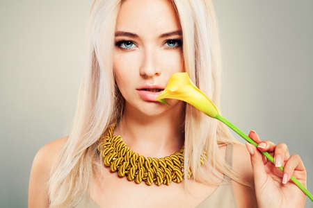 Beautiful Blonde Woman with Healthy Blond Hair, Makeup and Yellow Flowers. Cute Girl Fashion Model with Blonde Hairstyleの写真素材