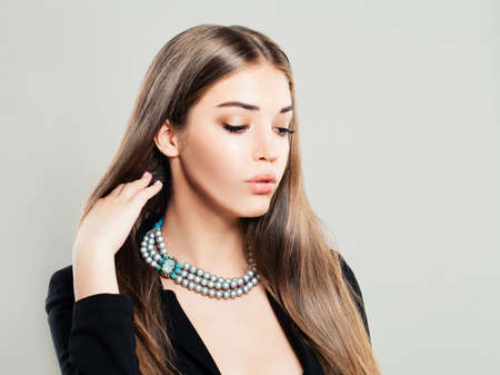 Beautiful Young Fashion Model Woman with Pearls Jewellery and Makeup on Banner Backgroundの写真素材