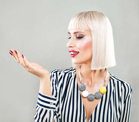 Happy Surprised Woman Showing Empty Copy Space on the Open Hand. Empty Hand, Fashion Makeup, Blonde Hairの写真素材