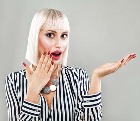 Surprised Fashion Model Woman Showing Empty Copy Space on the Open Hand. Empty Hand, Fashion Makeup, Blonde Bob Hairstyle, Fashion Clothの写真素材