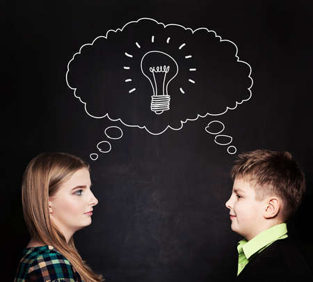 Cute Girl and Boy with Lightbulb at the Blackboard. Communication, Ideas and School Conceptの写真素材