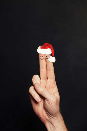 Christmas Couple. Two Happy Christmas Face Fingers in Santa Hats on Blackboard Backgroundの写真素材