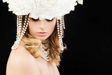Beautiful Woman with Blonde Curly Hairstyle, Makeup and Flowers onBlack Background with Copy Spaceの写真素材