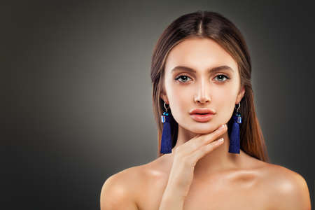 Perfect Woman  Fashion Model with Shiny Makeup and Blue Silky Jewelry Earrings on Background with Copy spaceの写真素材