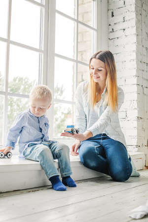 Cheerful Mother and Little Son Playing with Wooden Toys at Homeの写真素材