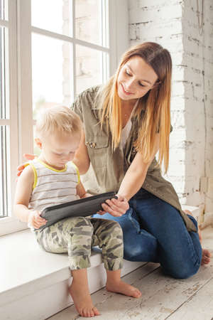 Cheerful mom and son using digital tablet at home.の写真素材