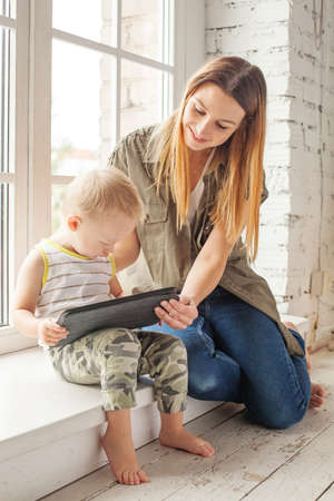 Happy mother with baby using tablet pc computer and learning at homeの写真素材