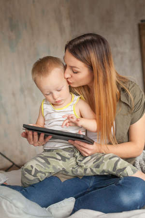 Happy mother with child boy and tablet pc computer at homeの写真素材