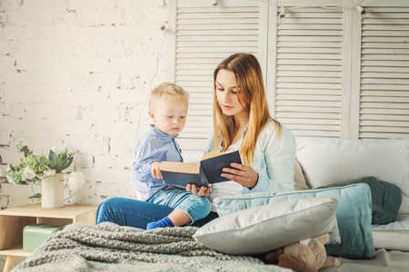 Pretty Young Mother Reading a Book to her Son.の写真素材