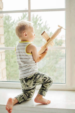 Small boy playing with wooden plane toy at home.の写真素材