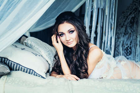 Glamorous Brunette Woman in White Retro Bedroomの写真素材