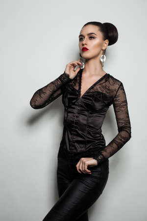 Fashion Model Woman in Black Clothes Standing against Gray Wall Backgroundの写真素材