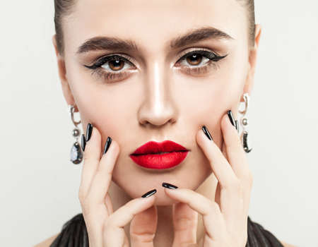 Beautiful Woman Touching her Face her Hand with Manicure. Black Nails and Makeup Lips with Red Color Lipstickの写真素材