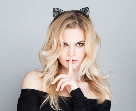 Alluring Woman with Black Lacy Cat Ears holding her finger to her lips in a gesture for silence or secretの写真素材