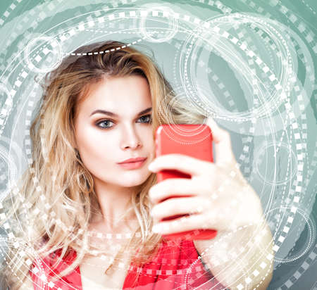 Beautiful woman making selfie photo on smartphone on virtual technology backgroundの写真素材