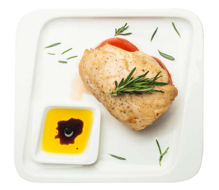 Chicken breast with tomato and rosemary on white plate isolated on white background, top viewの写真素材