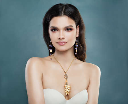 Cheerful Brunette Woman with Gem Earrings and Necklace. Cute Female Model in Jewelry Portraitの写真素材