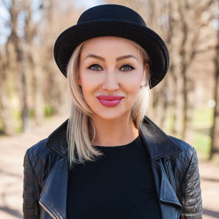 Fashion Portrait of Beautiful Female Model in Black Hat Outdoors. Beautiful Female Face Closeupの写真素材