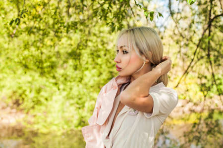 Blonde woman outdoors on green foliage leaves backgroundの写真素材