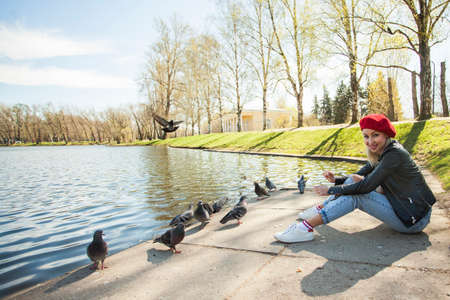 Outdoor portrait of young beautiful woman in park of european city. Model wearing red beretの写真素材