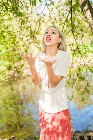Blonde woman outdoors on green foliage leaves background. Facial expressions and gestures. Female modelの写真素材
